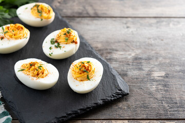 Homemade hard Boiled Deviled Eggs garnished with herbs on wooden table. Copy space