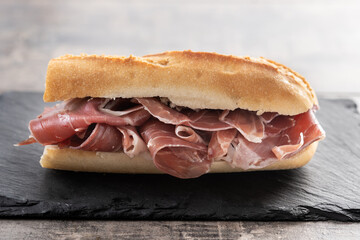 Traditional Spanish Serrano Ham Sandwich on wooden table	