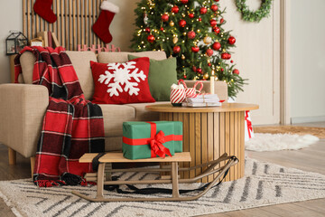 Interior of festive living room with white sofa, sled, gifts and Christmas tree