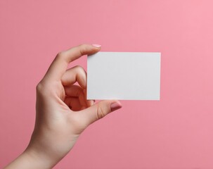Obraz premium Close-up of a hand holding a blank white card against pink
