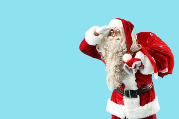 Santa Claus with bag full of gifts looking at something on blue background