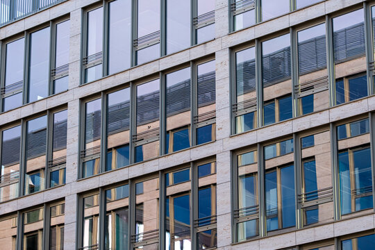 Contemporary office facade with glass and metal elements showing modular rhythm and reflections used as background for architecture or finance themes.