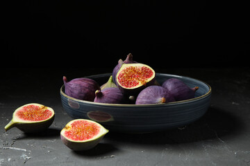 Bowl with fresh ripe figs on black table