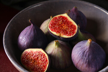 Bowl with fresh ripe figs on red background, closeup