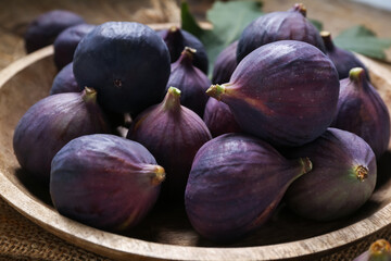 Bowl with fresh ripe figs on fabric as background, closeup