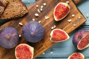 Composition with cutting board, fresh ripe figs and toast on blue wooden background, closeup