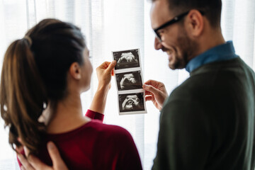 Woman and her boyfriend holding up an image of her sonogram of the baby. New family, love, baby