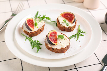 Plate of sandwiches with fresh ripe fig on white checkered fabric as background, closeup