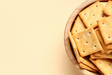 Wooden bowl with tasty crackers on beige background, closeup