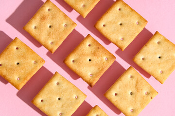 Composition with tasty crackers on pink background, closeup