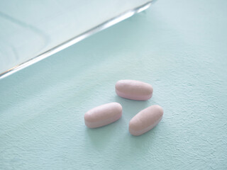 Three purple pills against and bottle of water on a light blue background. Health supplement concept. Space for your text.