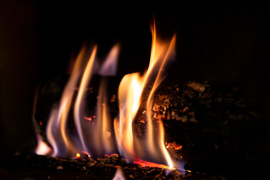 Flammes entourant une b&ucirc;che de bois dans un feu de chemin&eacute;e en gros plan, arri&egrave;re plan noir
