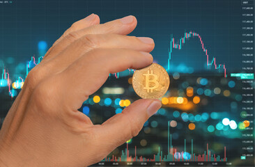 Hand holding bitcoin in front of digital blockchain chart at night with city lights in the background