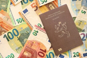 Luxembourg passport lies on big amount of euro money banknotes. Rich life and travel in Europe