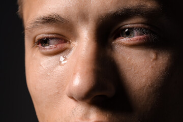Obraz premium Sad man crying on black background, closeup