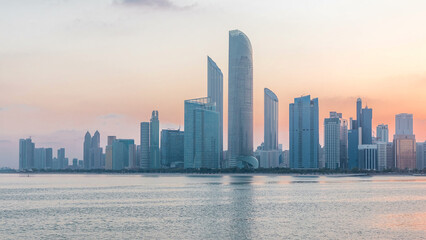 Abu Dhabi city skyline with skyscrapers before sunrise with water reflection night to day timelapse