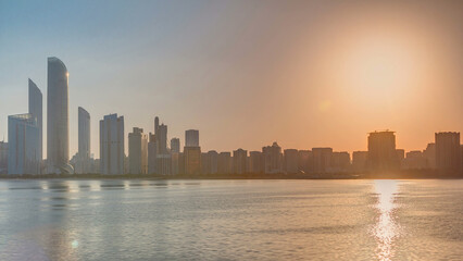 Fototapeta premium Abu Dhabi city skyline on sunrise time with water reflection timelapse.