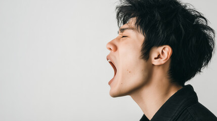 若い男性があくびをして眠そうにしている写真