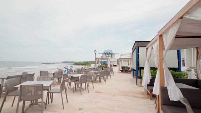 Empty tables and chairs at a seaside cafe terrace on a cloudy day overlooking the ocean, colombia