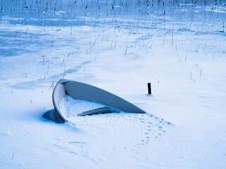 Frozen boat rests in a serene winter landscape on a lake in Sweden