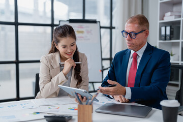Business professionals engaging in a corporate meeting, analyzing charts and graphs on a digital tablet while discussing important financial data and strategies