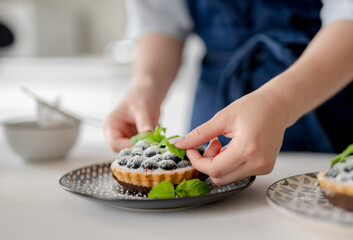Girl Decorating Blueberry Dessert With Mint Leaves