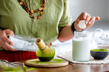 Woman Adding Ice To Matcha Latte