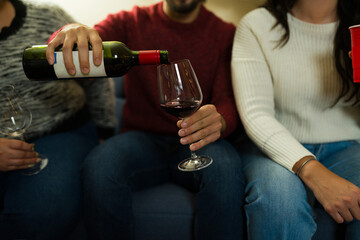 Hands of a man pouring red wine during holiday reunion celebration