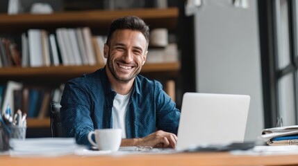 Fototapeta premium Portrait of smiling young businessman doing online research over laptop while sitting at desk in office
