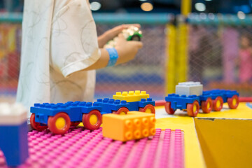 Kid happy face playing with plastic bricks. Child play with blocks plastic in indoor playground. Cute boy playing toy colorful blocks. Preschool activities and early childhood education.