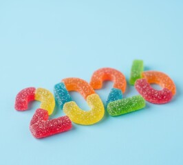 Colorful gummy candies, shaped as numerals, against a pastel blue background