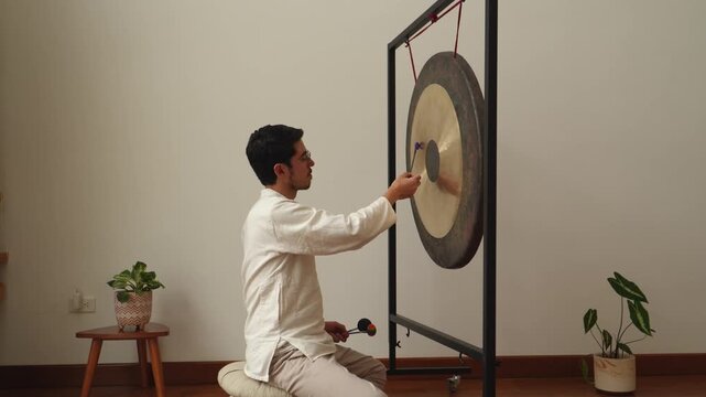 Man is making music with a gong and flummies