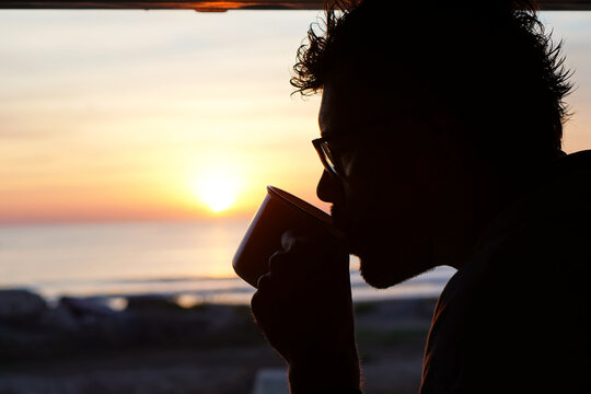 camper life. young man drinking coffee at dawn in his camper van