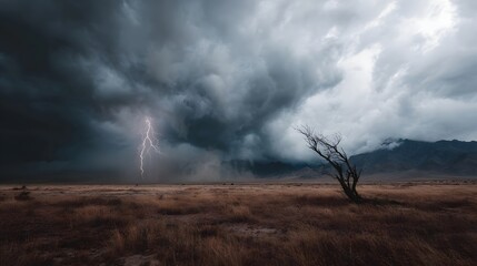 Dramatic lightning strike illuminates a solitary dead tree in a dry storm swept landscape under dark ominous clouds