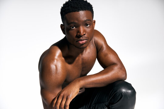 Muscular African American man showcases his strength and confidence in studio setting - Powered by Adobe