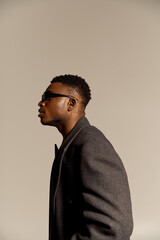 Obraz premium Stylish african american man in grey coat showcases autumn fashion in a studio setting