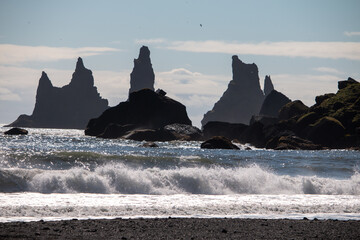 Dramatic Silhouettes of Jagged Sea Stacks Against a Bright Coastal Sky with Crashing Waves