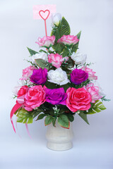 Elegant artificial rose bouquet in pink, purple, and white arranged in a ceramic vase with a heart-shaped card holder, symbolizing love, warmth, and timeless beauty — ideal for romantic or home decor.