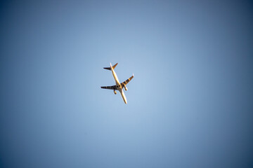 Commercial Passenger Jet Soaring High Above in a Vast Expansive Clear Blue Sky on a Sunny Day