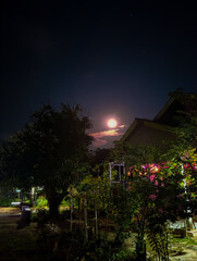 Full moon above peaceful rural night house