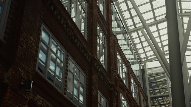 A striking atrium featuring red brick walls, tall arched windows, and a glass ceiling, bathed in natural light for a fresh and open feel.