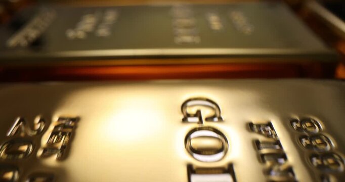 Gold bars lie in row and reflect warm glow across surface. Bullion stack shows weight and serial marks symbolizing wealth and reserve in bank vault
