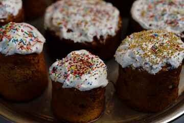 Colorful decorated cakes on a silver tray at a festive gathering in a kitchen setting during the day