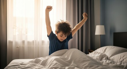 A young boy stretching his arms after waking up in a bright bedroom.
