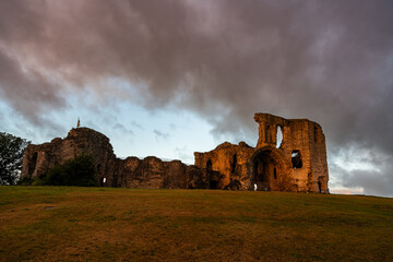 Obraz premium Warm early sunlight illuminating the ancient stone ruins of Denbigh Castle under dramatic morning clouds