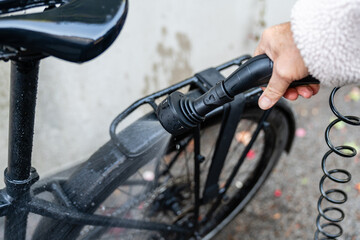 Mann reinigt schwarzes Fahrrad mit Wasser und Gartenschlauch Pflege des Fahrradrahmens und...