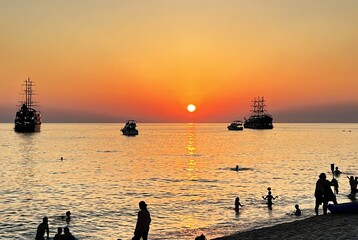 Majestic sunset on the sea with old ship. Vibrant sunset on the beach