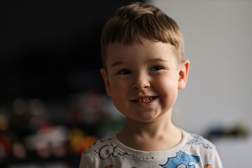 Smiling toddler boy in natural light wearing a cartoon shirt