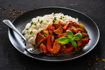 Polish lecho with white rice - bell pepper tomato stew with sausages on black table