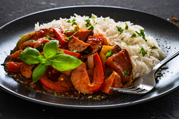 Polish lecho with white rice - bell pepper tomato stew with sausages on black table